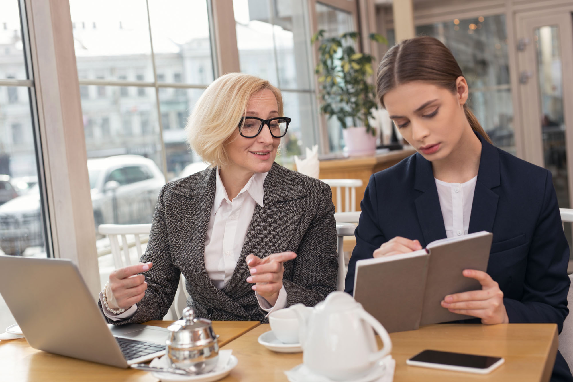 2 women working with a laptop and book