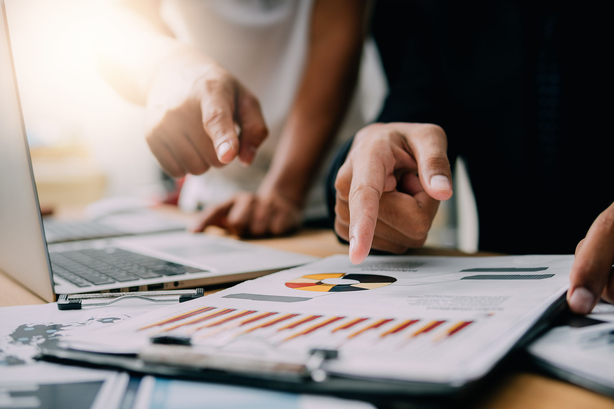 2 people pointing at business charts